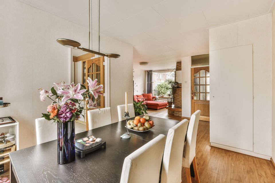 Dining room with dark table, white chairs, and flower arrangement.
