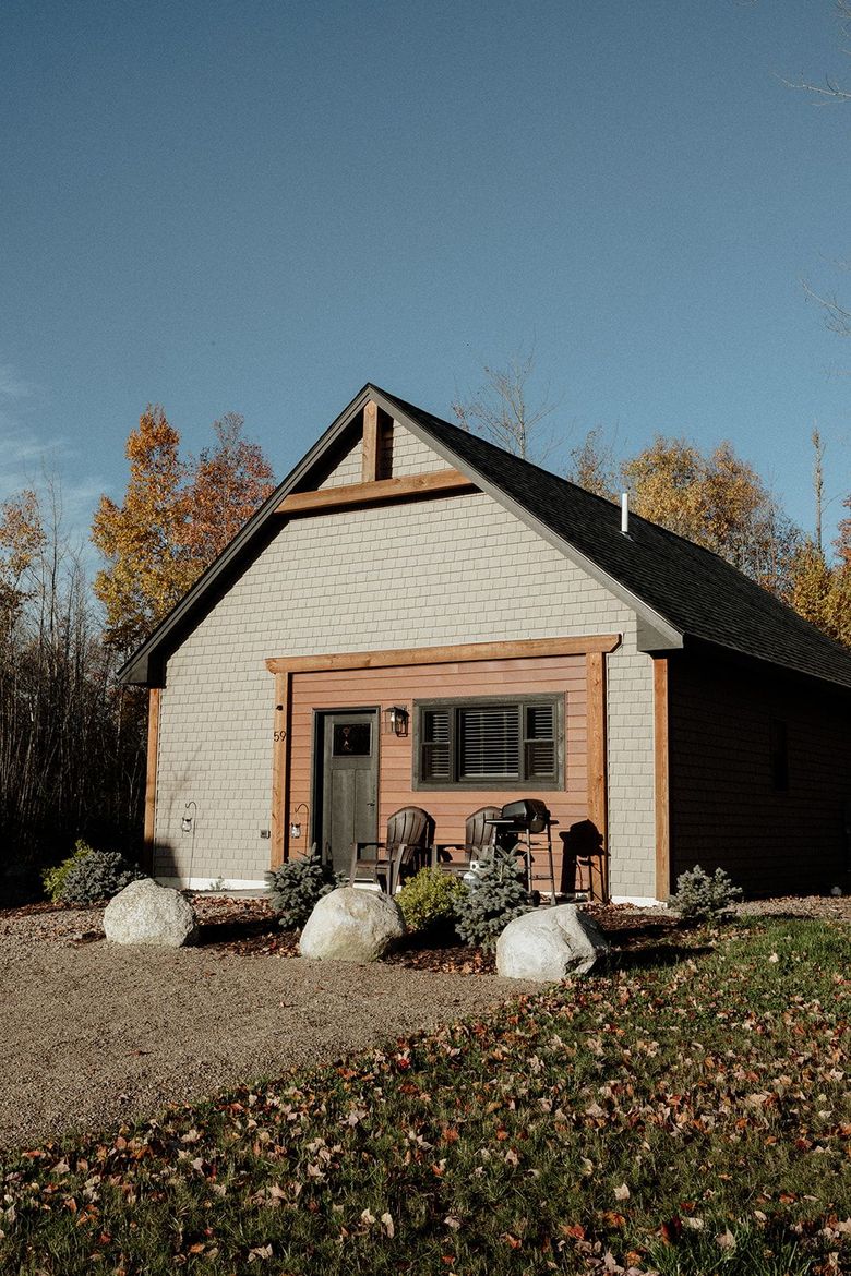 Exterior of a building under construction, featuring brown wooden trim, siding, a door, a window, and a clear blue sky.