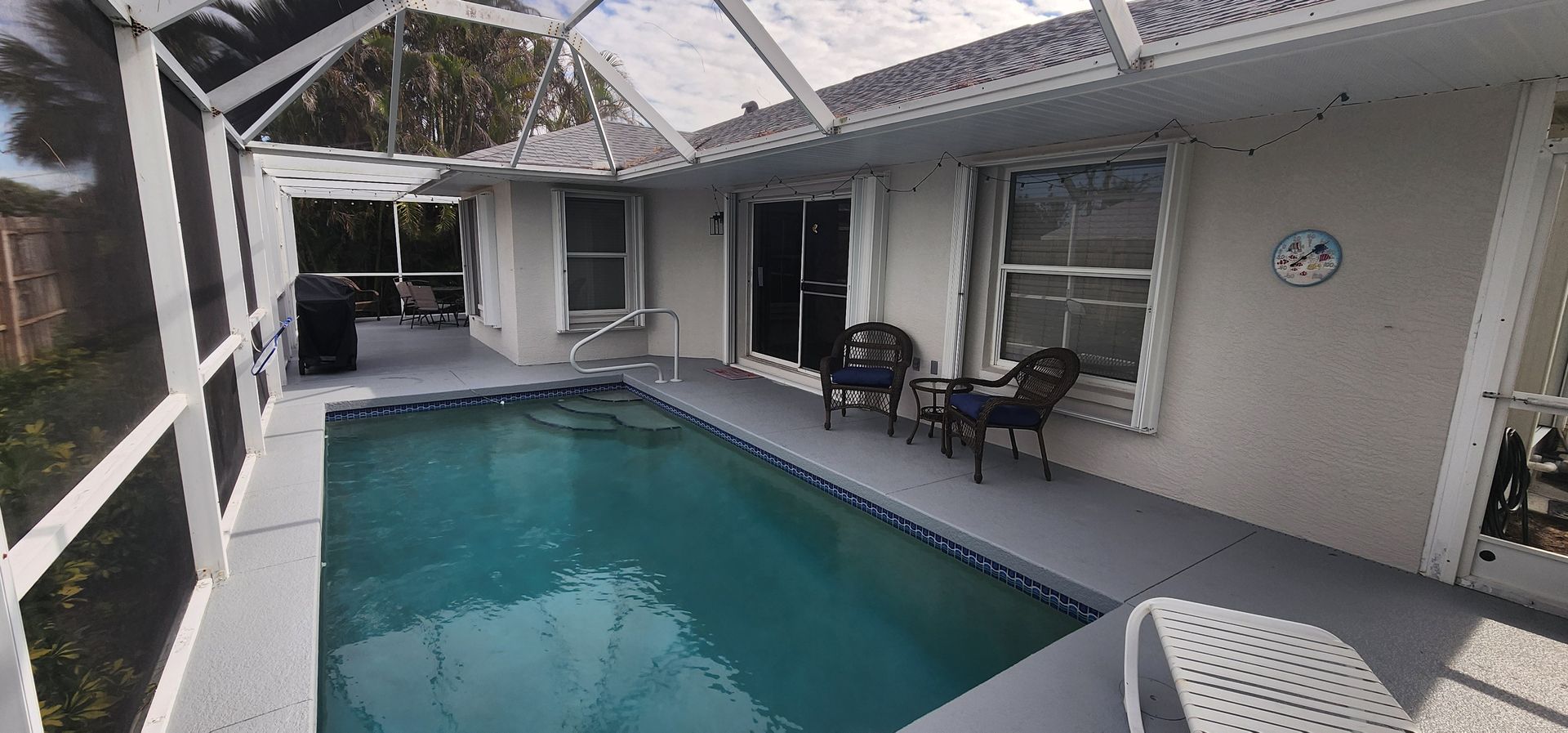 Covered patio with a small pool, lounge chairs, and sliding glass doors in a tropical courtyard.