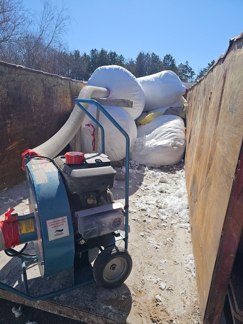 A snow blower is sitting on a cart next to a pile of snow.