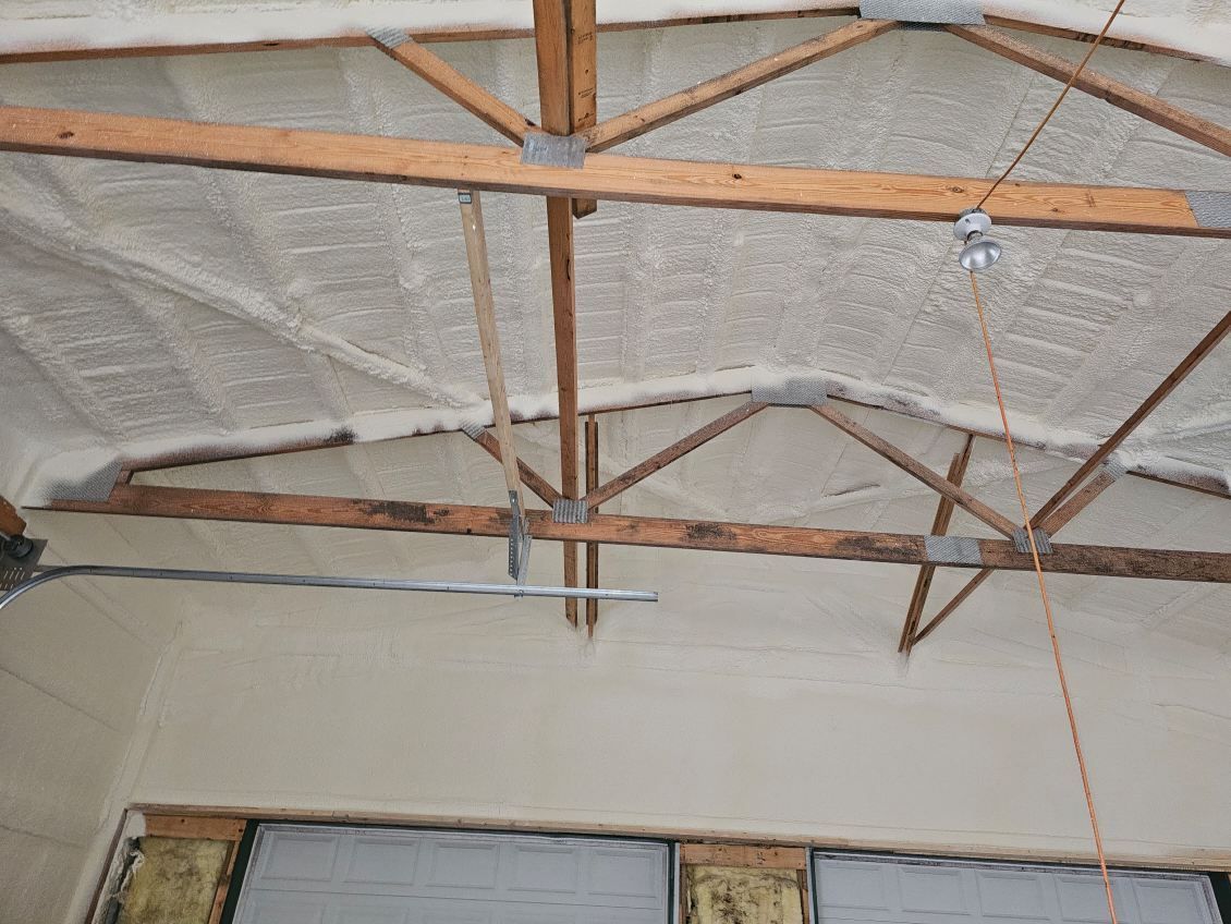 The ceiling of a garage with wooden beams and insulation.