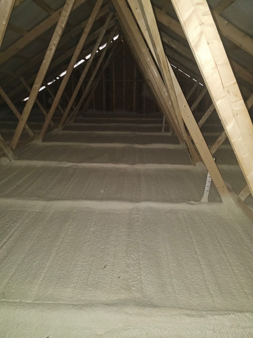 The inside of an attic with wooden beams and a concrete floor.
