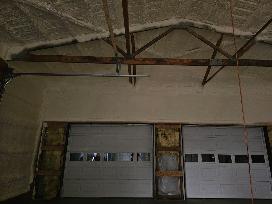 A garage with two garage doors and a ceiling covered in foam.