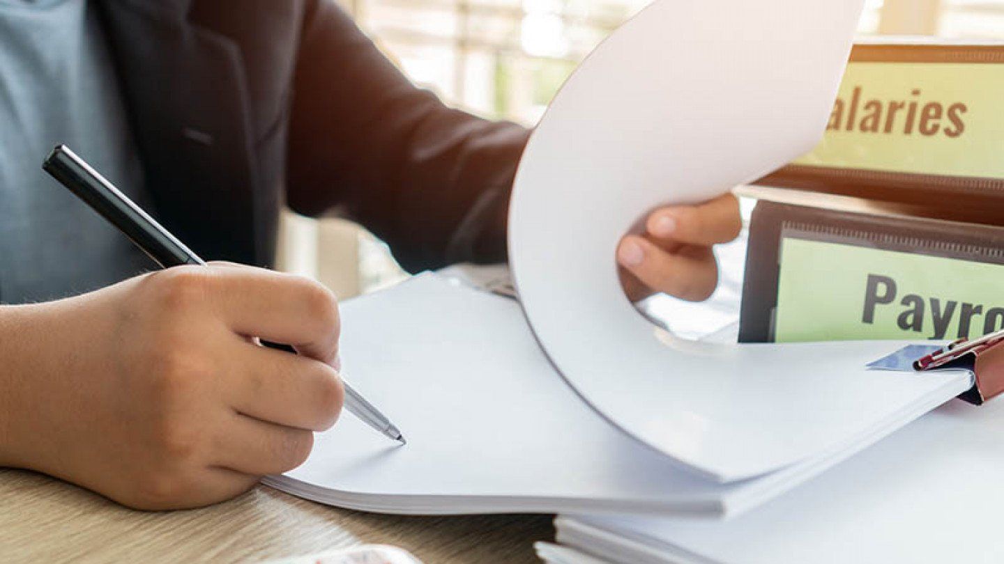 a person is writing on a piece of paper with a pen .