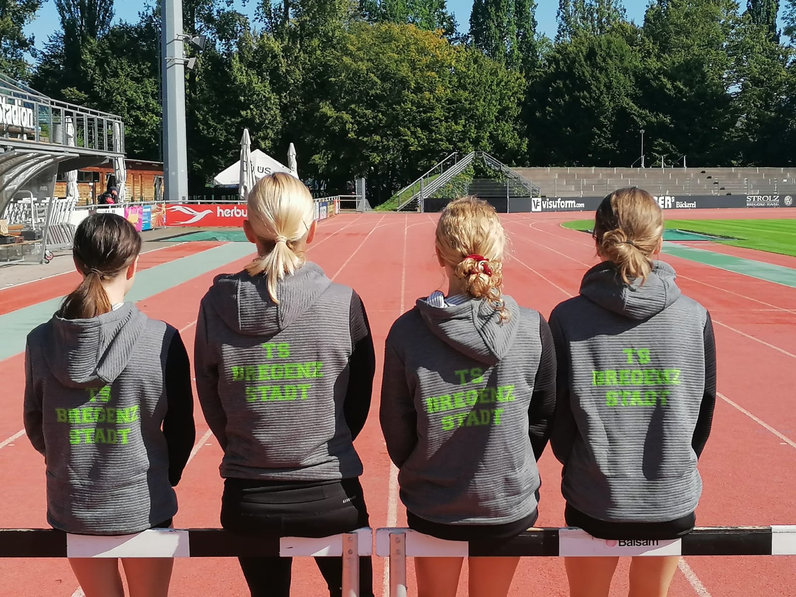Eine Gruppe von Mädchen sitzt auf einer Hürde auf einer Strecke