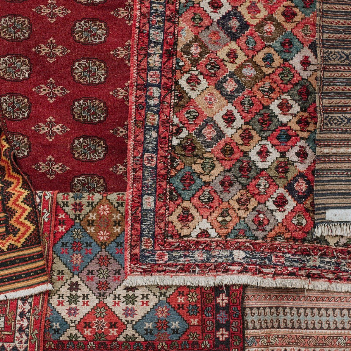 A collage of various hand-woven rugs featuring intricate geometric patterns, floral motifs, and a palette of red tones.