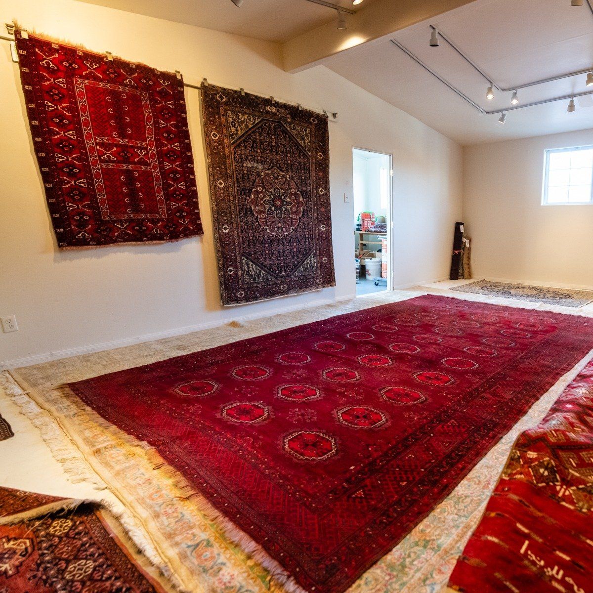 A rug showroom with decorative area rugs hanging on the walls and spread across the floor.