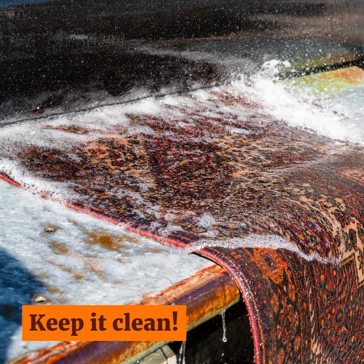 A rug with intricate patterns being washed with soapy water on a flat surface, with the text 
