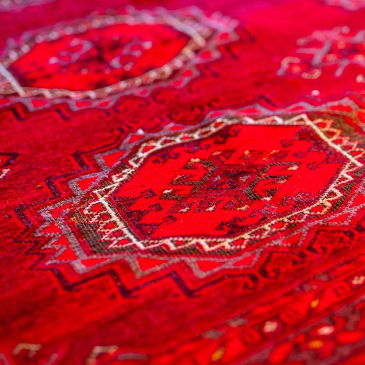 Close-up of a vibrant red rug featuring traditional geometric patterns and repeating octagonal motifs.