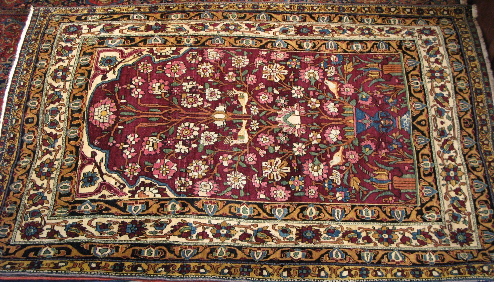 A rectangular rug with a deep red field featuring a floral 