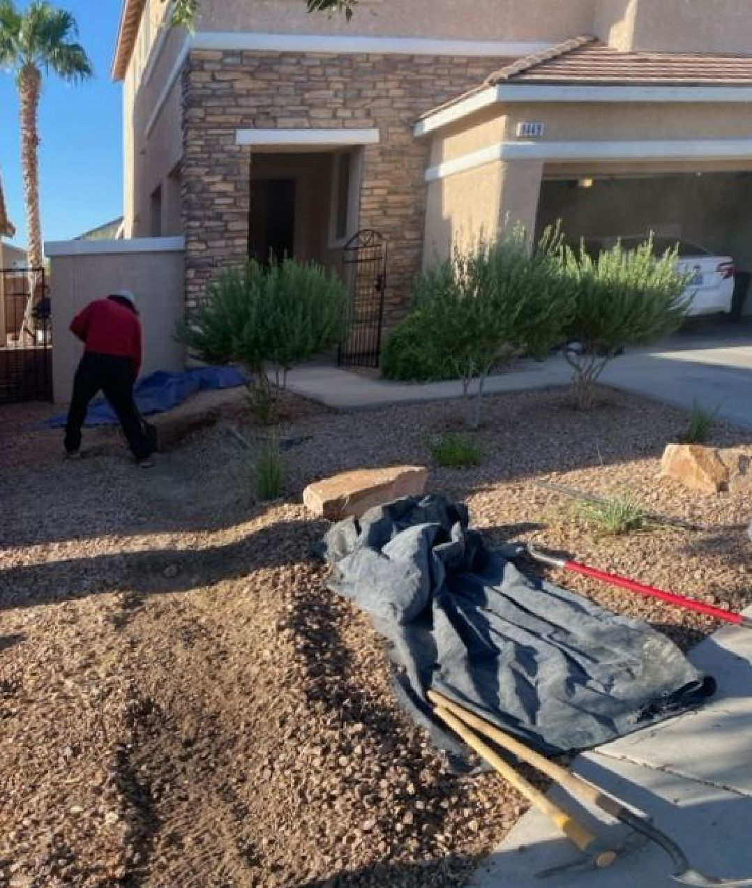A man is working in the dirt in front of a house