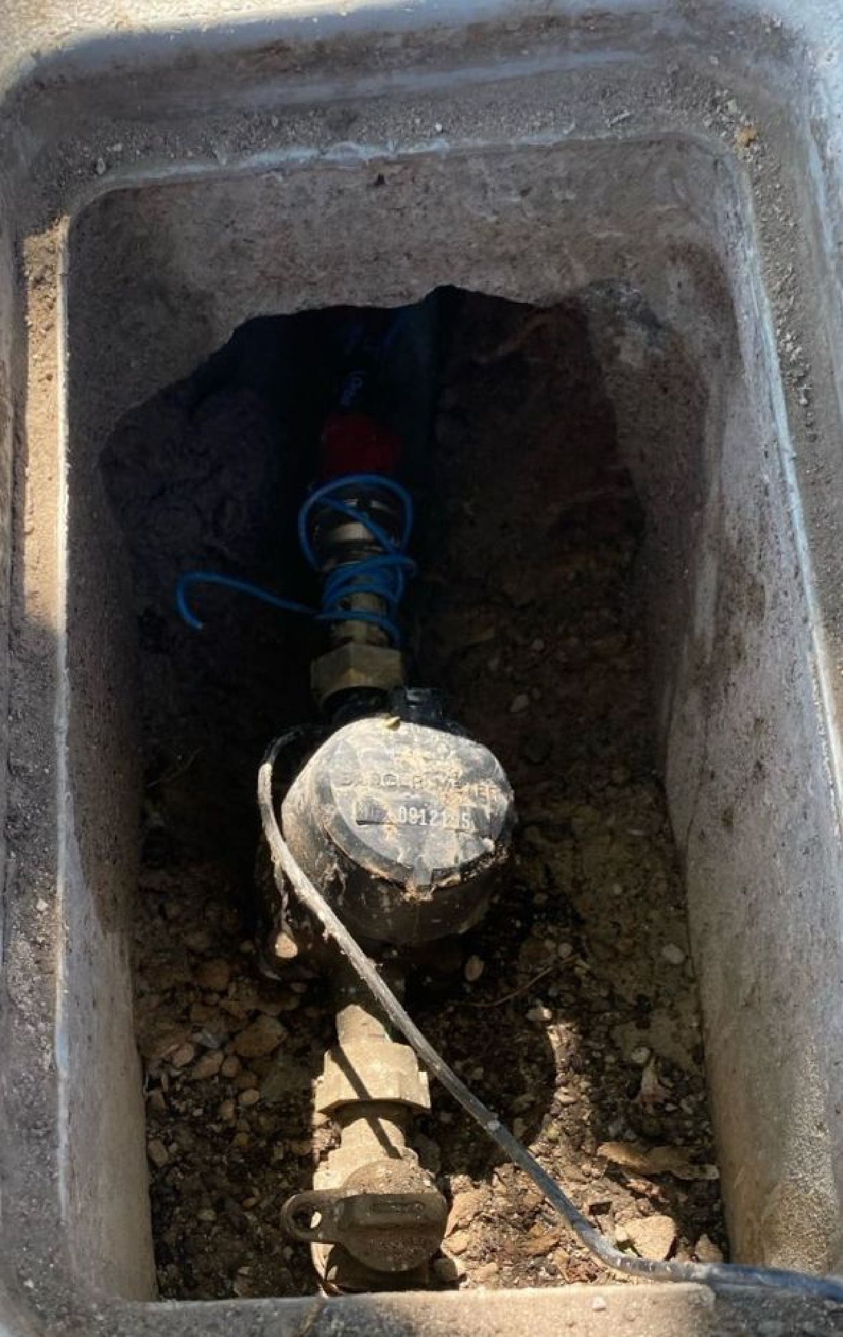 A water meter is sitting in a hole in the ground.