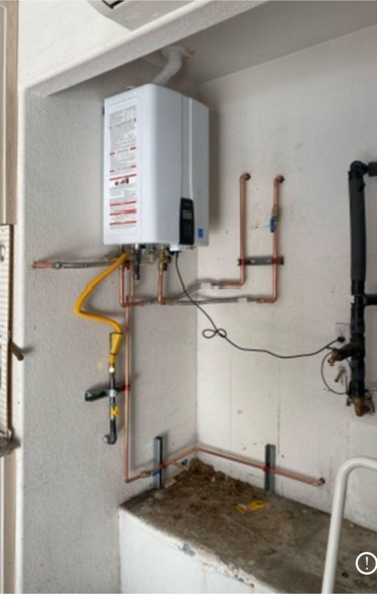 A water heater is hanging on a wall next to a sink.