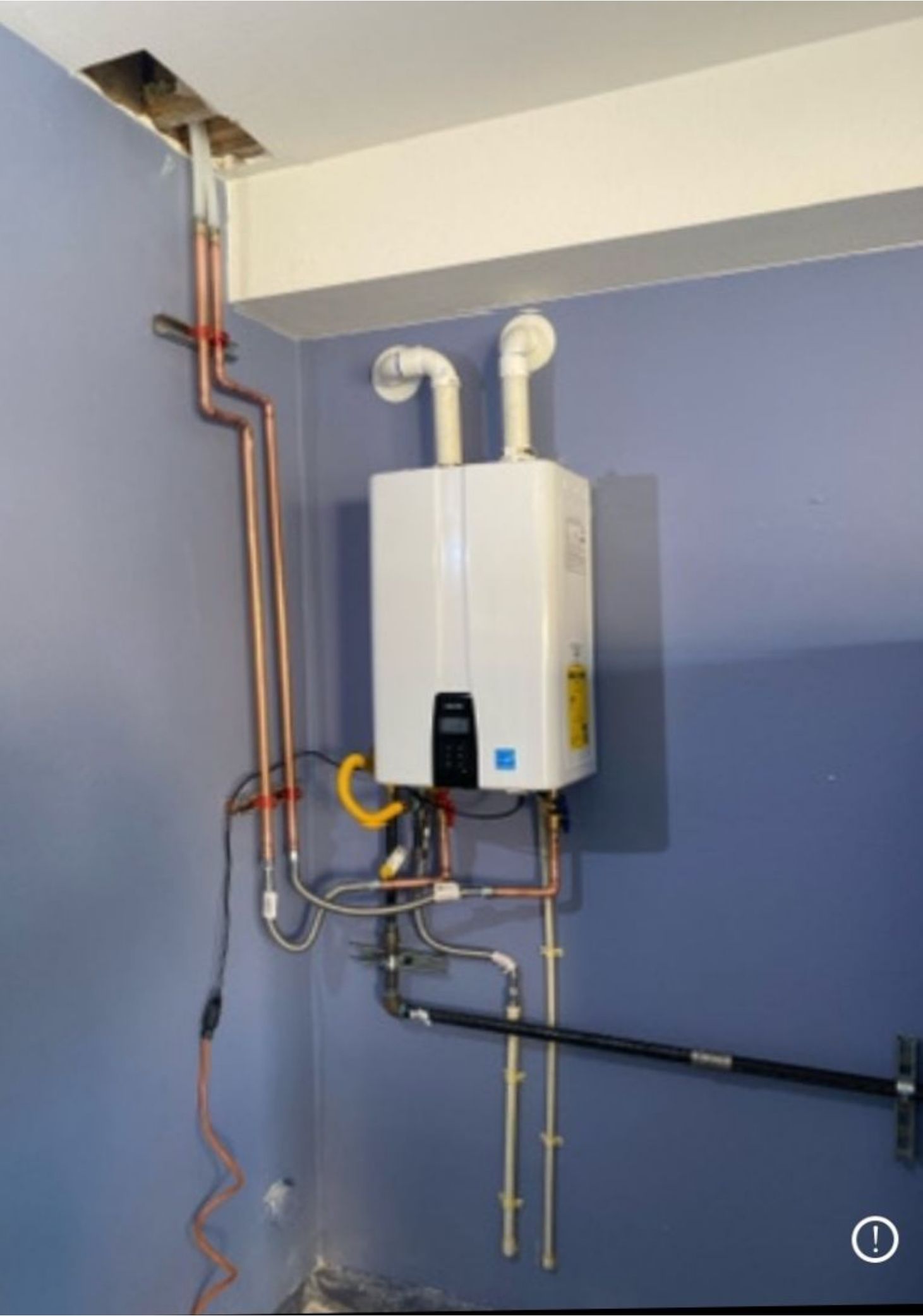 A white water heater is mounted to a blue wall