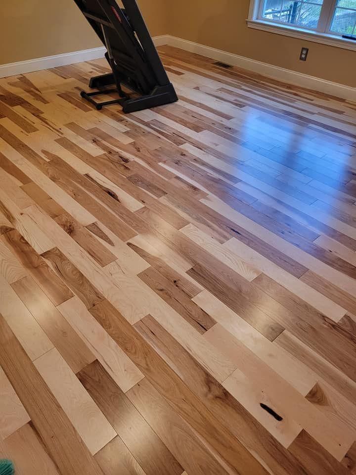 Shiny hardwood floor in a room with a treadmill and sunlight near a window.