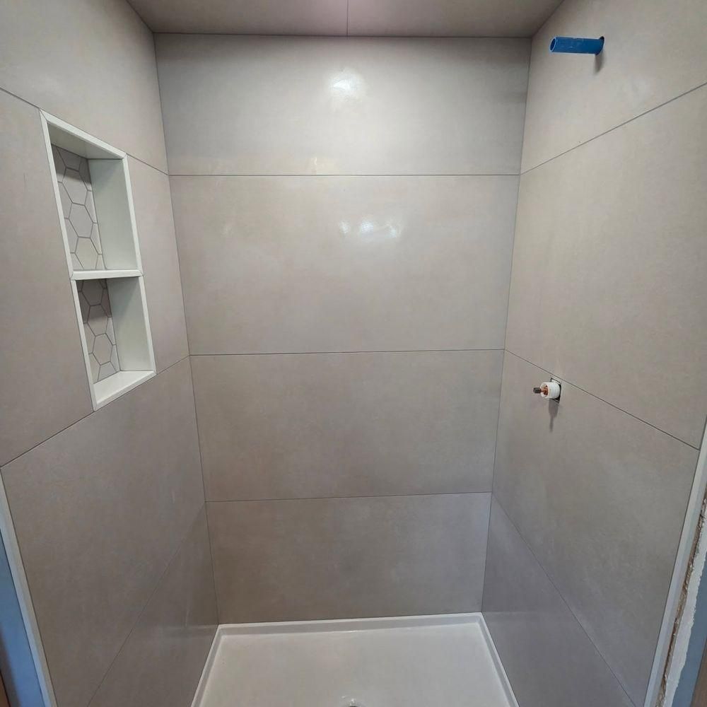 Small tiled bathroom or shower stall with gray walls, a niche shelf