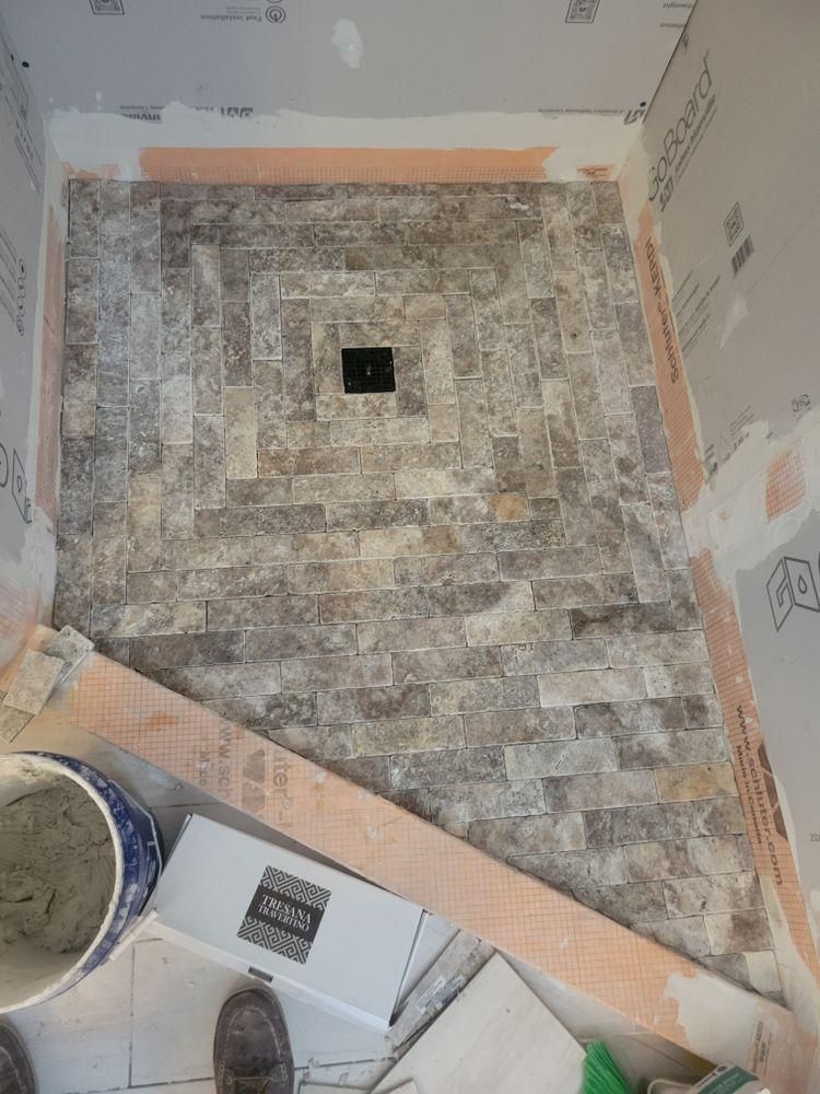 Small tiled shower or wet room under construction, viewed from above, with a drain in the center.
