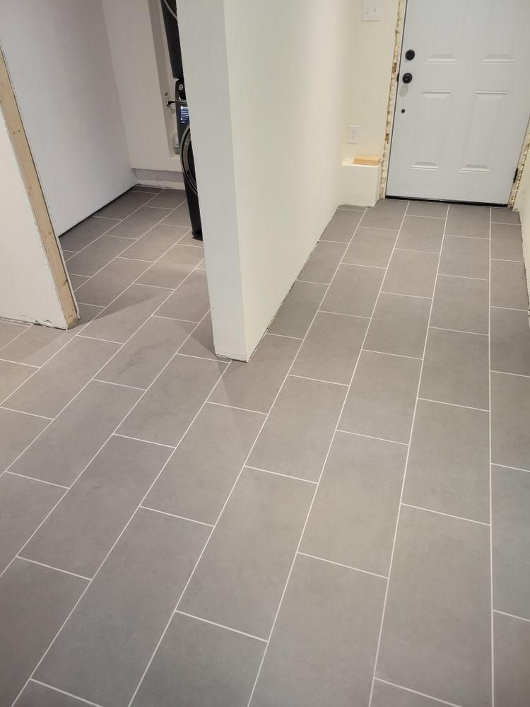 Empty tiled hallway with white doors and walls, viewed from an entryway.