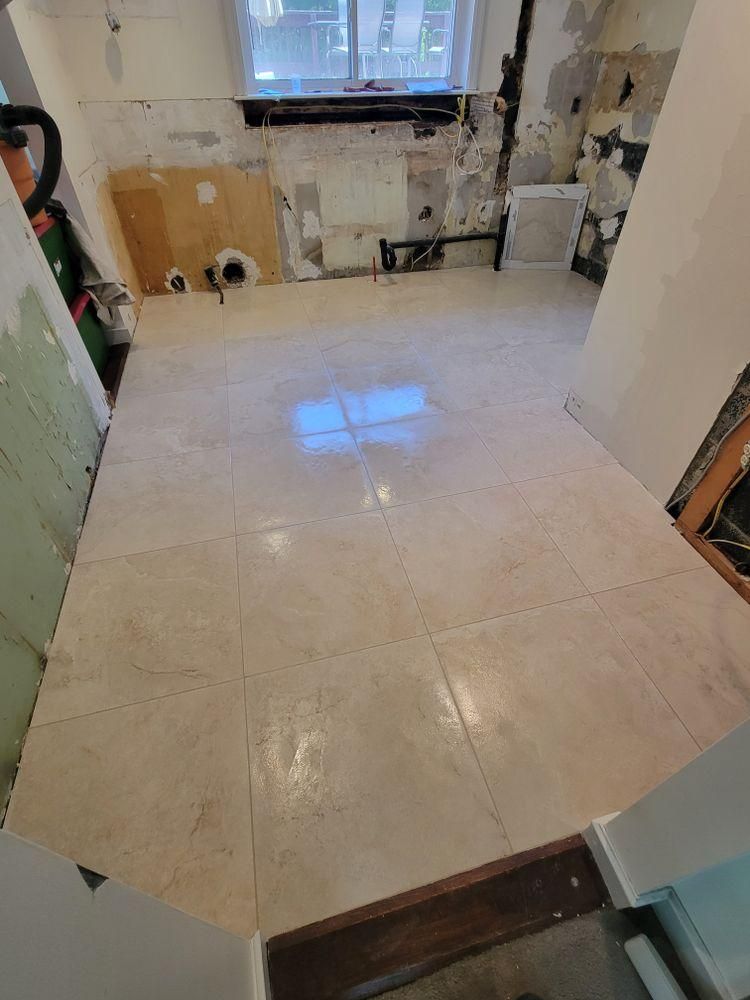 Empty tiled room under renovation with a window and wall patches on the far wall