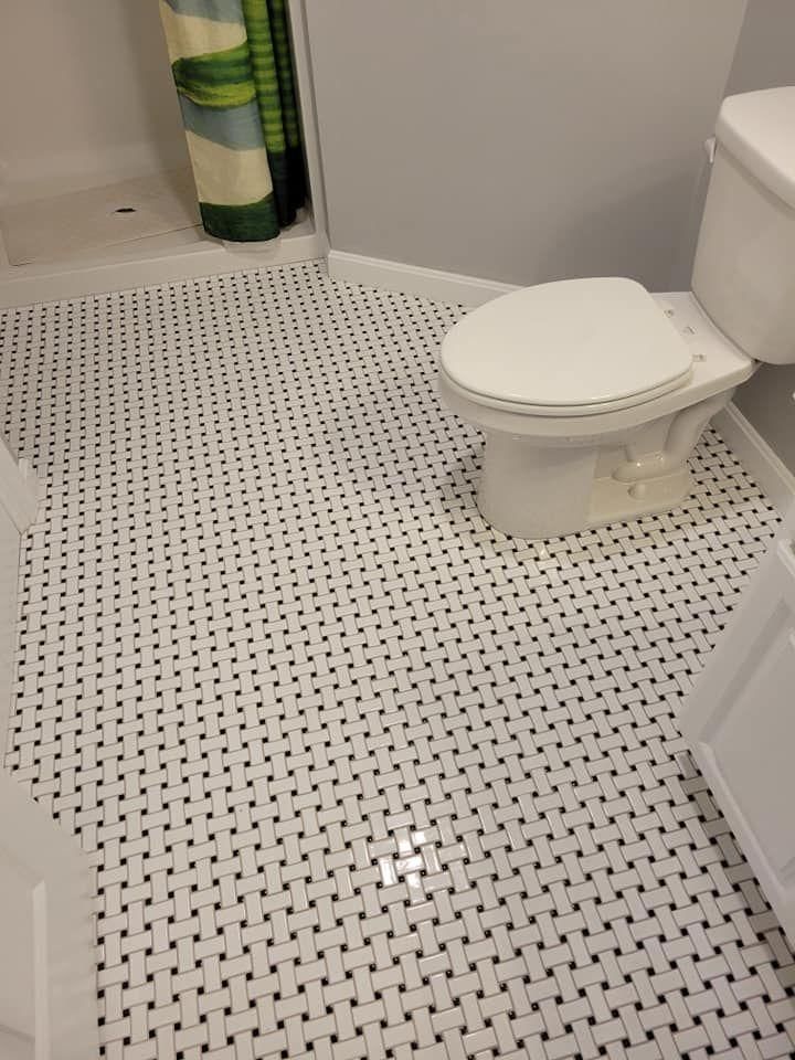 Small bathroom with white toilet and black-and-white mosaic tile floor.
