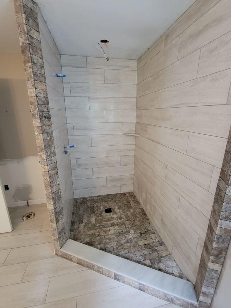 New tiled shower under construction with stone floor and beige wall tiles