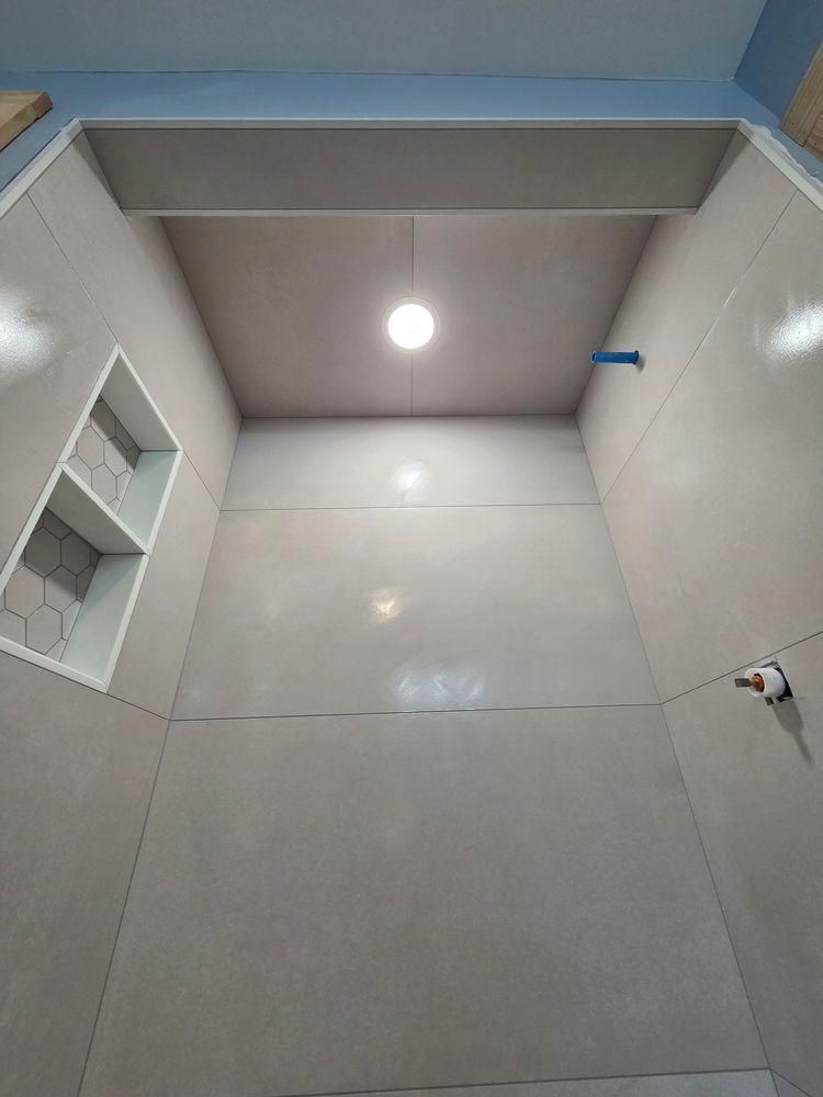 Small tiled bathroom with a skylight-like ceiling opening and a single light bulb.