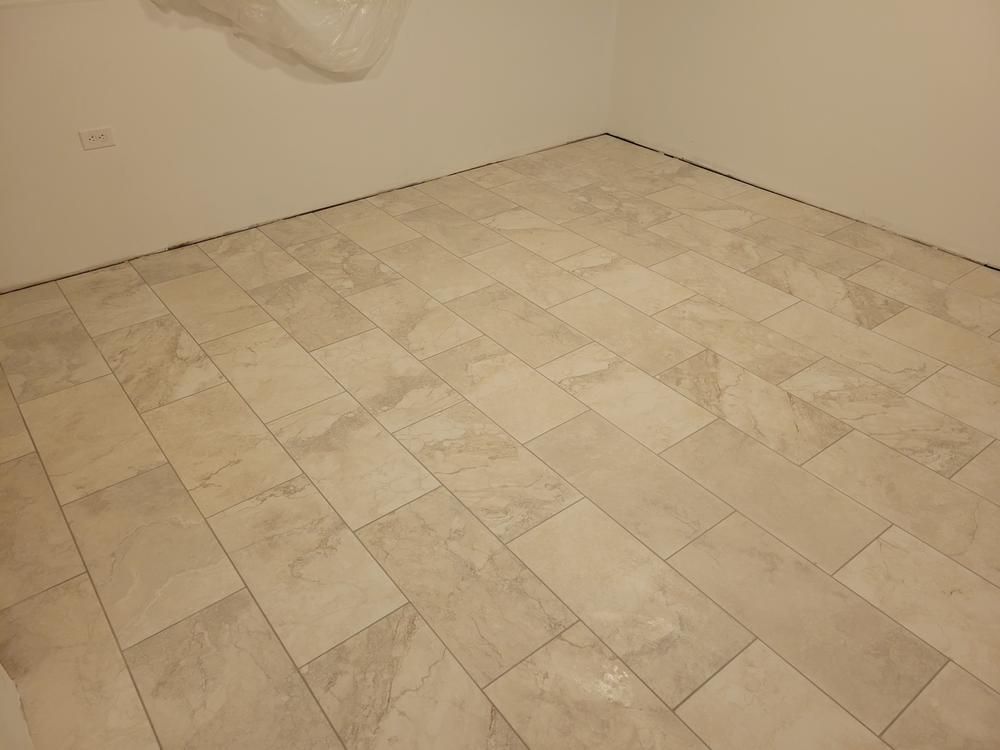 Empty tiled room with beige walls and light stone-patterned floor tiles.