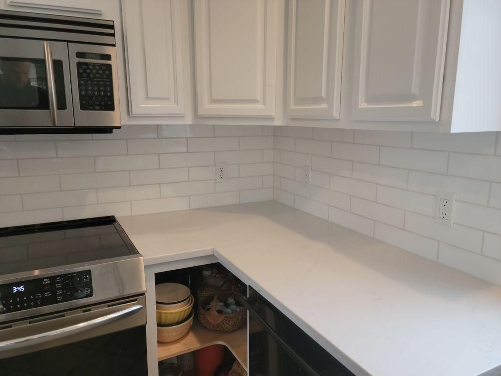 Empty white kitchen corner with stainless stove, microwave, and open cabinet under quartz countertop