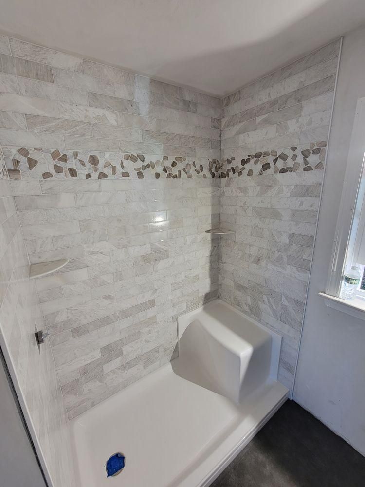 Accessible shower with white tile walls, built-in bench, and grab bar in a small bathroom.