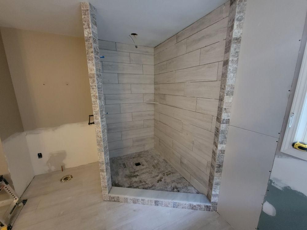 Bathroom under renovation with tiled shower stall and unfinished drywall around it