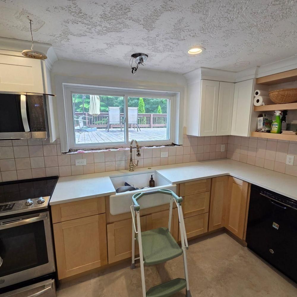 Kitchen with white cabinets, beige tile backsplash, a window over the sink, and a black stove and dishwasher.