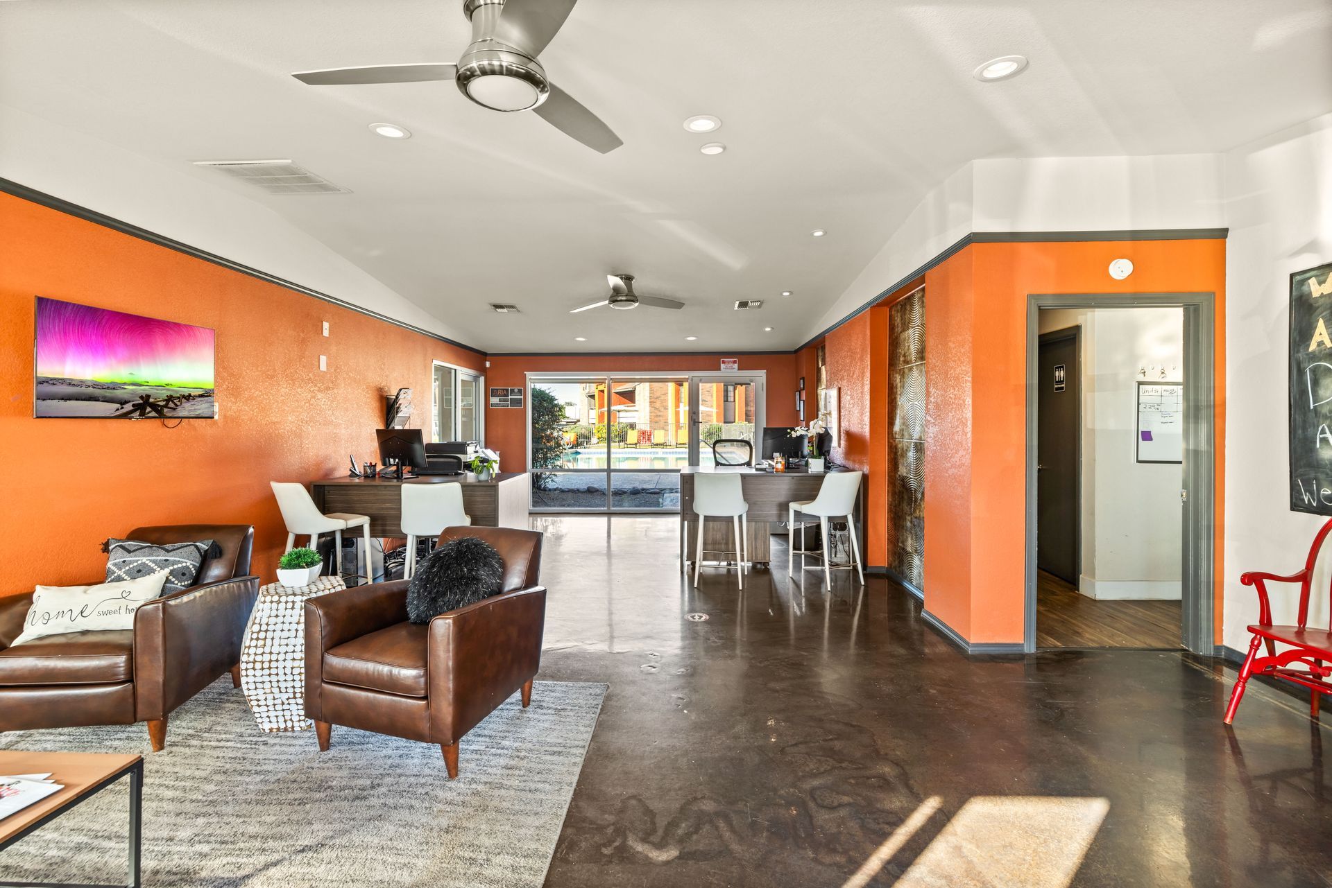 Interior of a modern waiting room with orange walls, leather chairs, and a front desk.