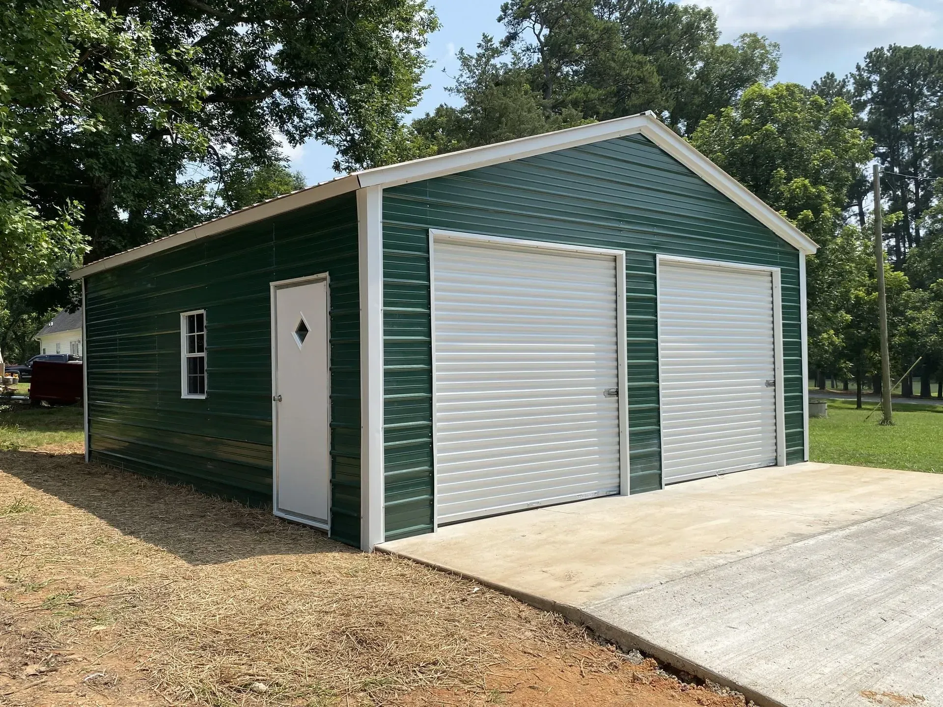 A green garage with white doors and a window
