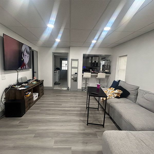 Modern living room with gray sectional sofa, wall-mounted TV, and wood-look flooring
