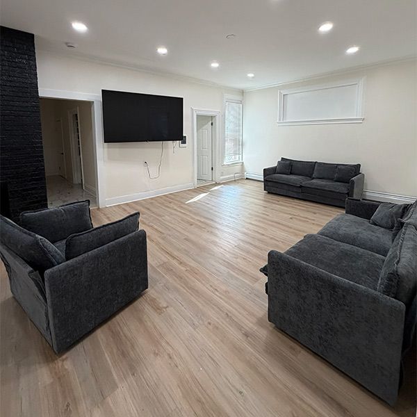 Spacious living room with gray sofas, a wall-mounted TV, and light wood flooring