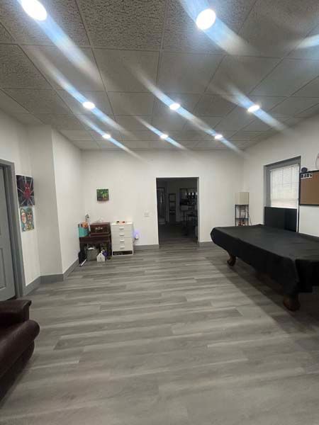 Spacious hall with gray flooring, bright ceiling lights, a black table, and a sofa