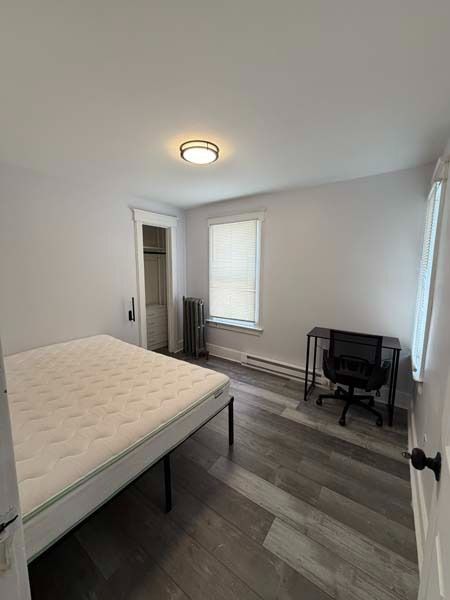 Small bedroom with bed, window, desk chair, and light gray flooring