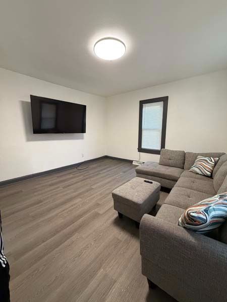 Modern living room with wall-mounted TV, gray sectional sofa, and wood-look flooring