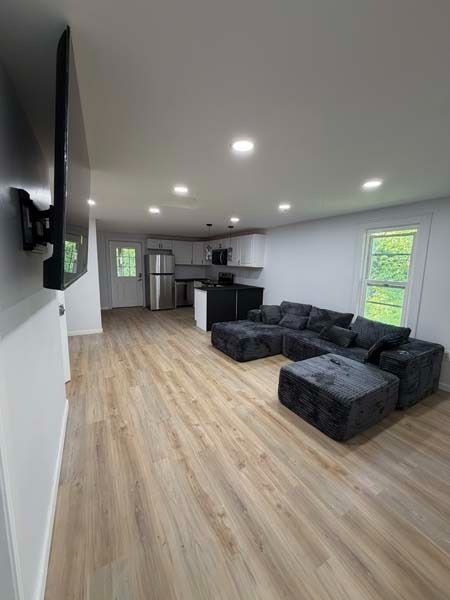 Spacious modern living room with gray sectional sofa, wood floors, and open kitchen area