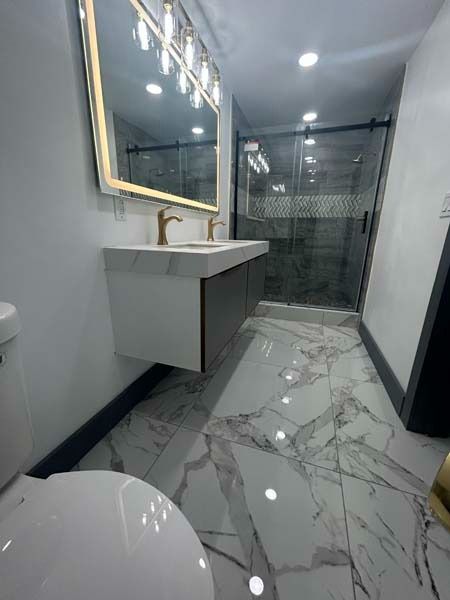 Modern bathroom with marble-pattern floor, floating sink, large mirror, and glass shower enclosure