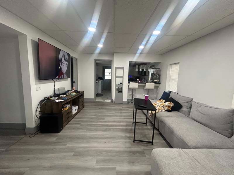 Modern living room with gray sectional, wall-mounted TV, and light wood floors