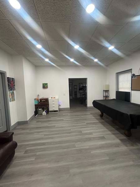 Spacious empty room with gray floors, white walls, tables, and recessed ceiling lights