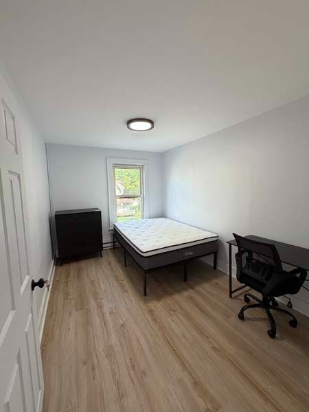 Minimal bedroom with bed, desk, chair, dresser, and a window.