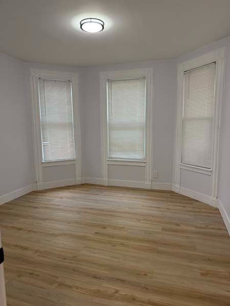 Empty white room with three windows and light wood flooring