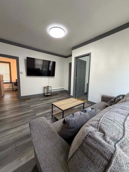 Modern living room with gray sectional, wall-mounted TV, coffee table, and gray wood flooring