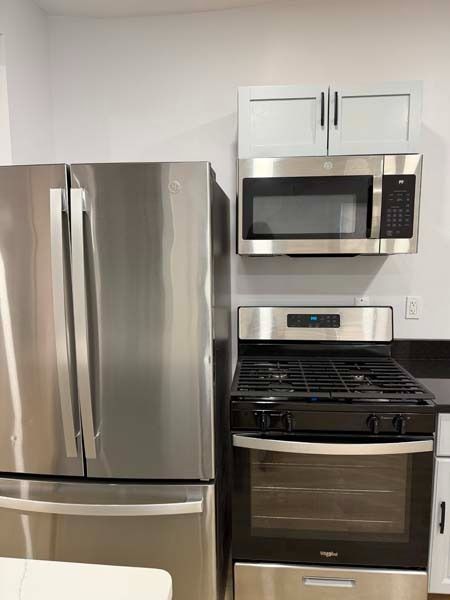 Stainless steel refrigerator, microwave, and gas stove in a modern kitchen.
