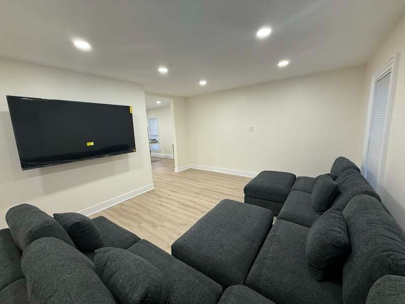 Modern living room with two dark gray sofas, wall-mounted TV, and light wood floors