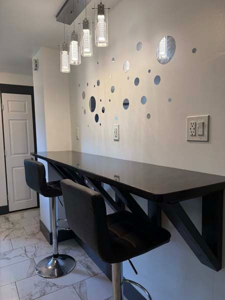Modern kitchen bar with black stools, pendant lights, and decorative wall decals