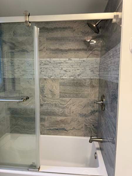 Modern bathroom tub-shower combo with glass sliding door and gray tile walls