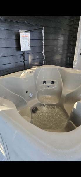 Indoor white hot tub with jets and built-in seats in a dark room